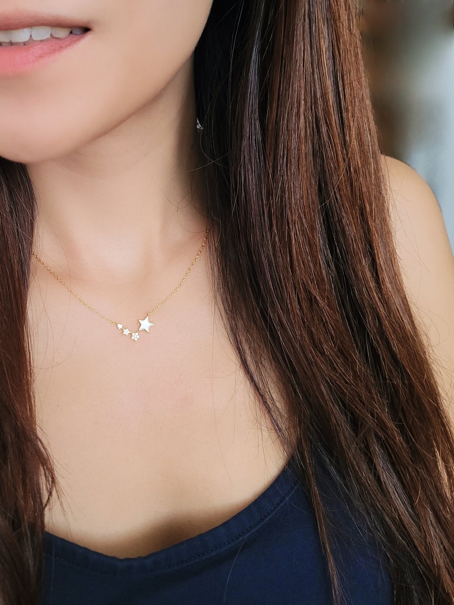 A stylish young girl showcases a luxurious gold necklace, highlighted by a radiant star charm, embodying timeless elegance.