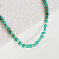 Close up of a Gold Turquoise beaded bracelet displayed on a white surface. Crafted in natural turquoise gemstone intersecting with gold vermeil beads.