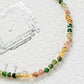 A multicolored tourmaline beaded bracelet with gold nuggets, displayed on a white surface.