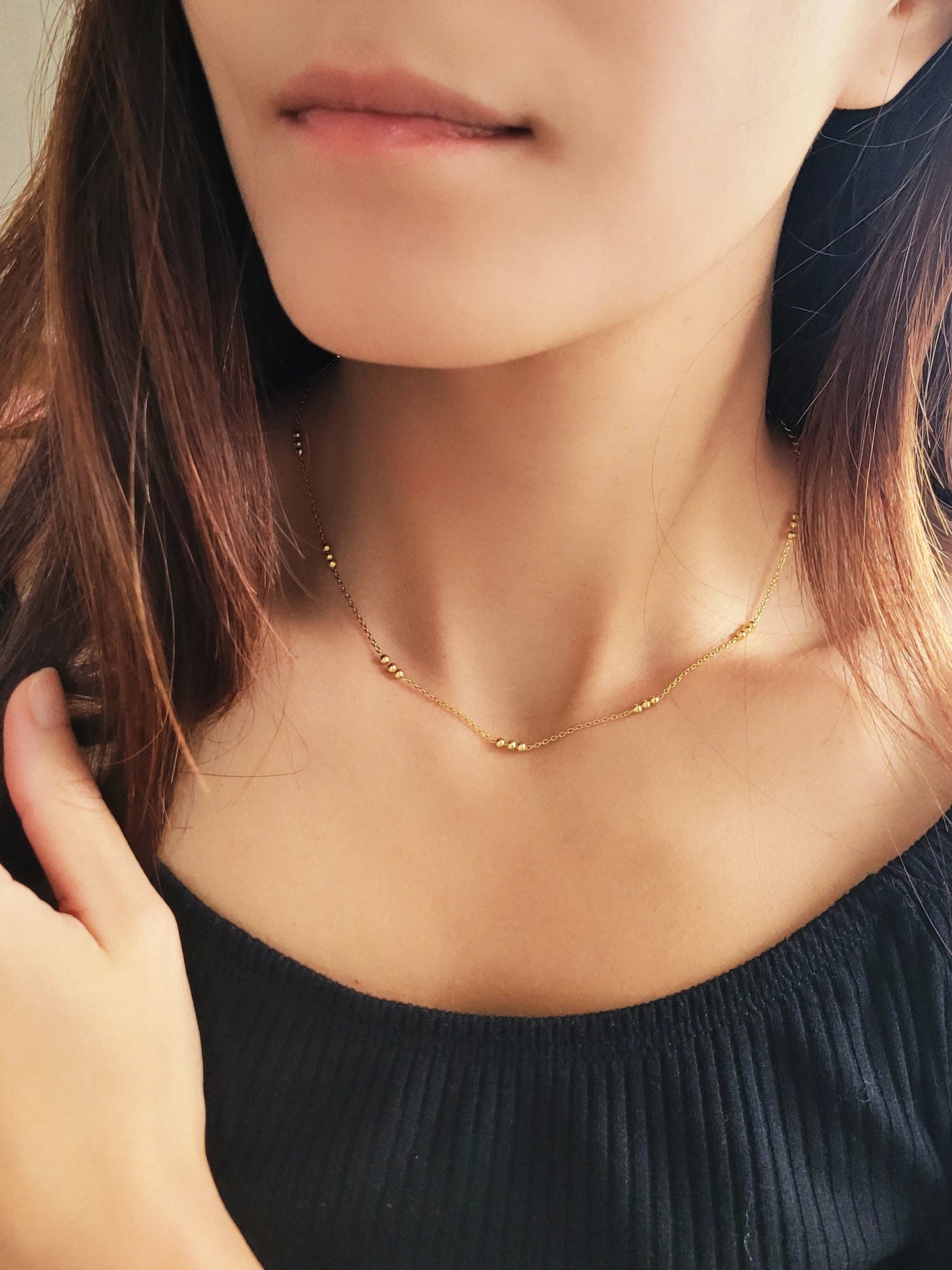 Close-up of a woman wearing a delicate 18ct gold vermeil triple ball necklace, showcasing its minimalist design with small gold beads spaced along a fine chain.