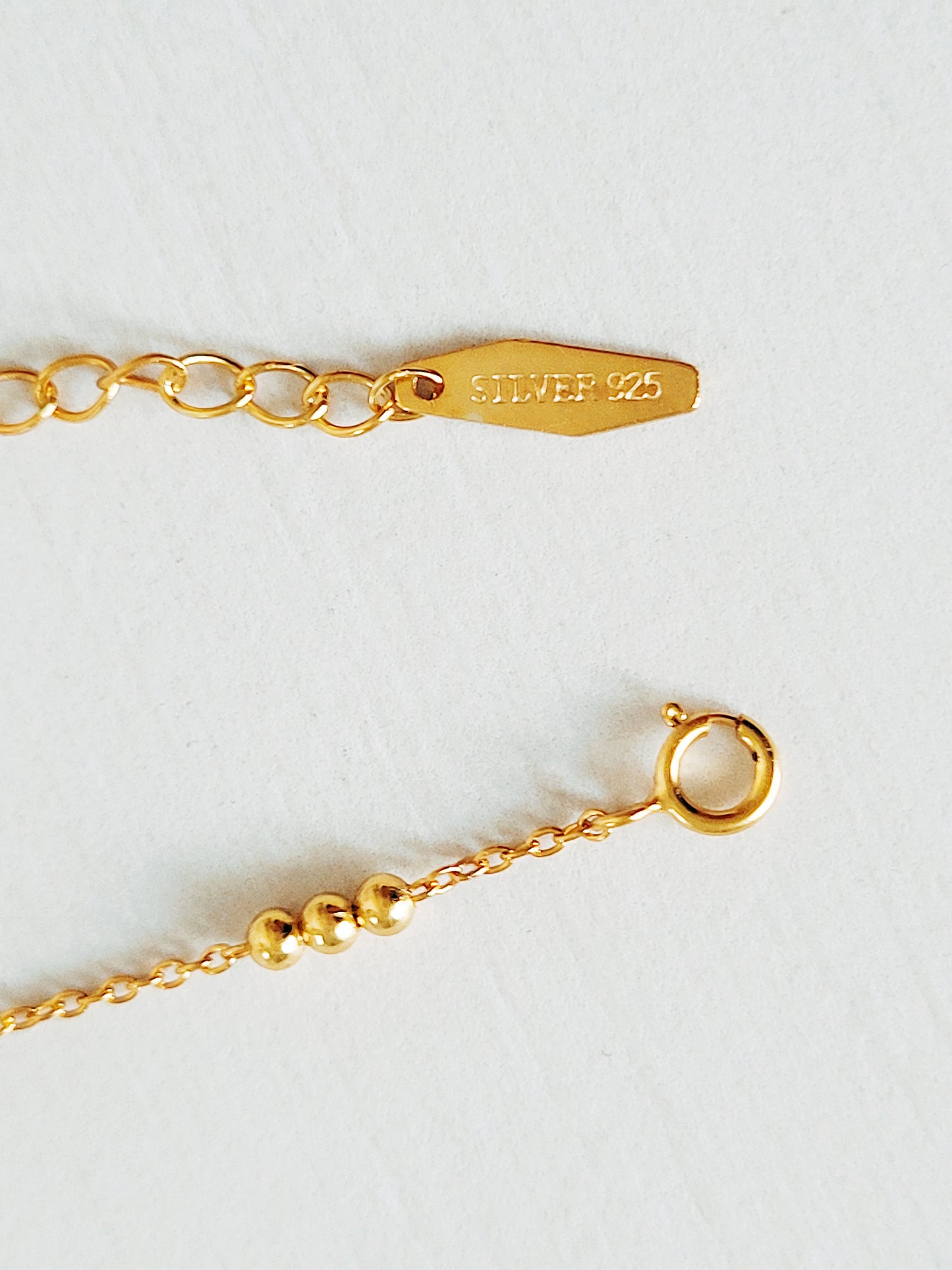 Close-up of the triple ball necklace closure using spring ring closure with gold plated 925 silver tag.