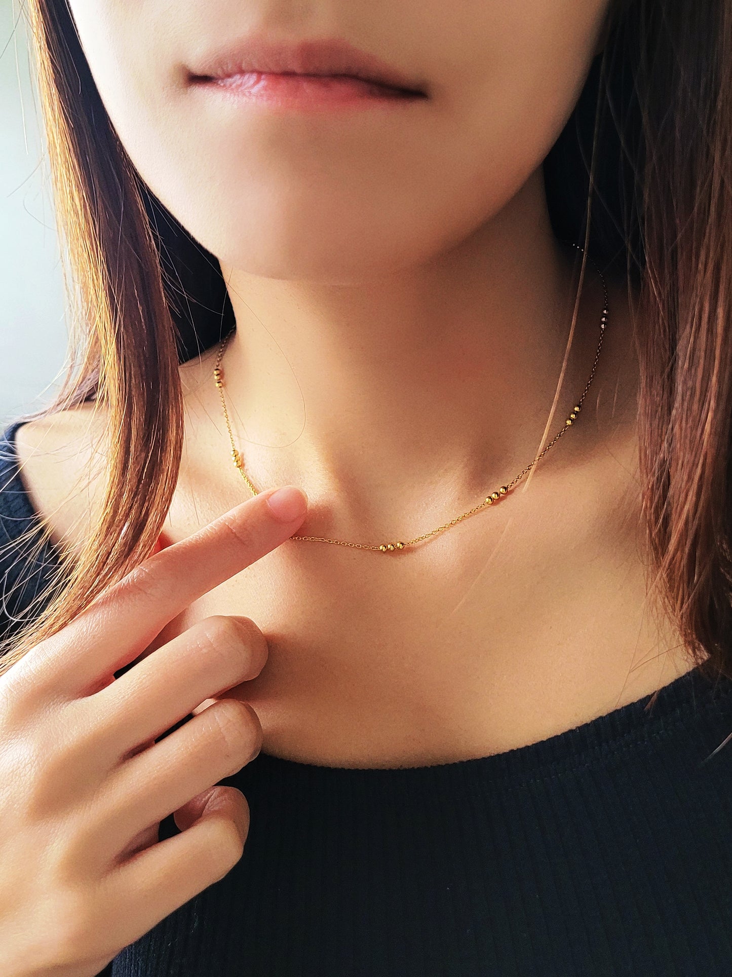 Close-up of a woman wearing a delicate 18ct gold vermeil triple ball necklace, showcasing its minimalist design with small gold beads spaced along a fine chain.