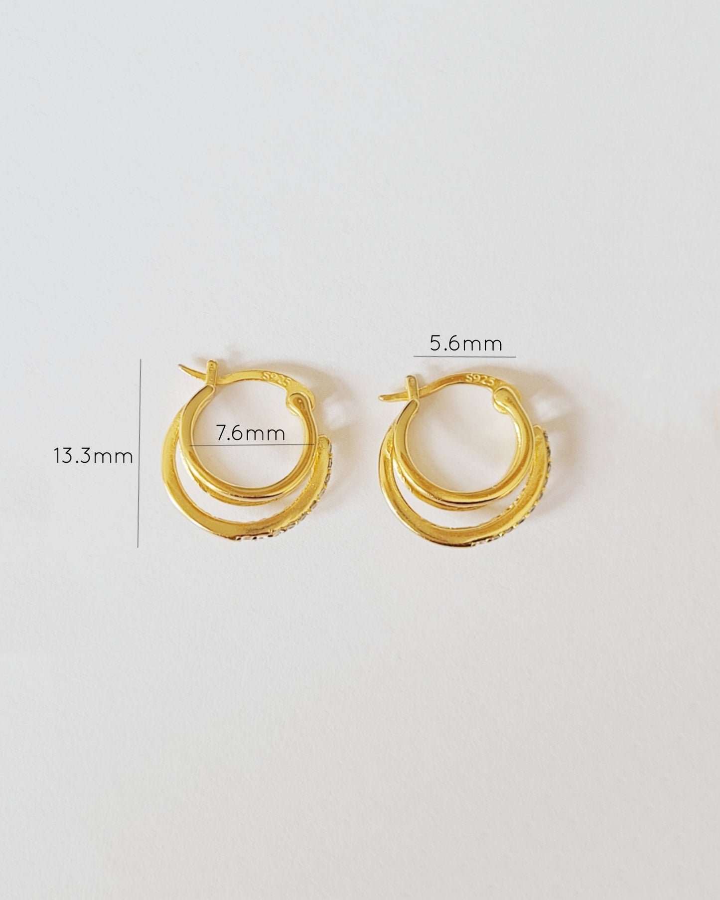 A pair of gold triple hoop earrings with detailed dimensions: 13.3mm in height, 7.6mm middle hoop width, and 5.6mm inner hoop width, showcasing their sleek and compact design.