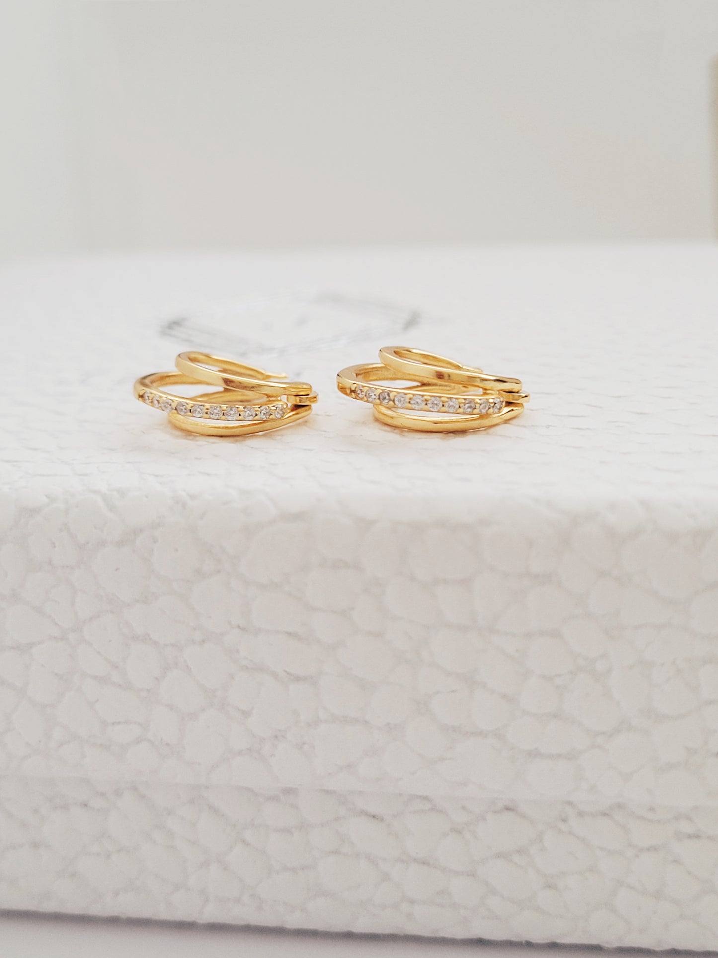 A pair of triple gold hoop earrings placed on a jewellery box.