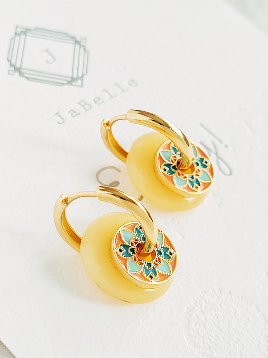Close-up of vintage tile-pattern-inspired gold hoop earrings with floral detailing, displayed on a white background.