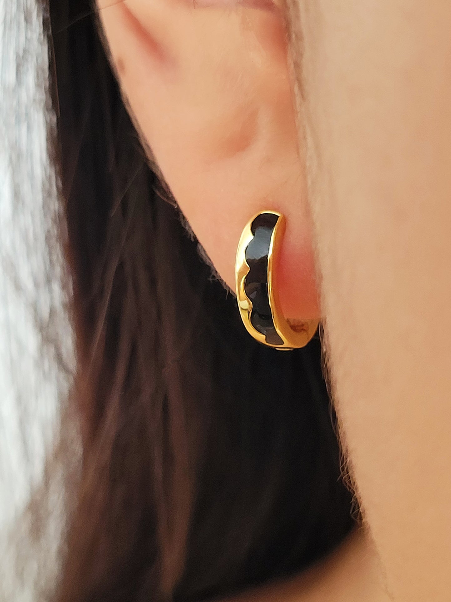 Gold and black hoop earring worn on a girl ear