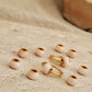Gold and beige jewelry pieces on a textured surface