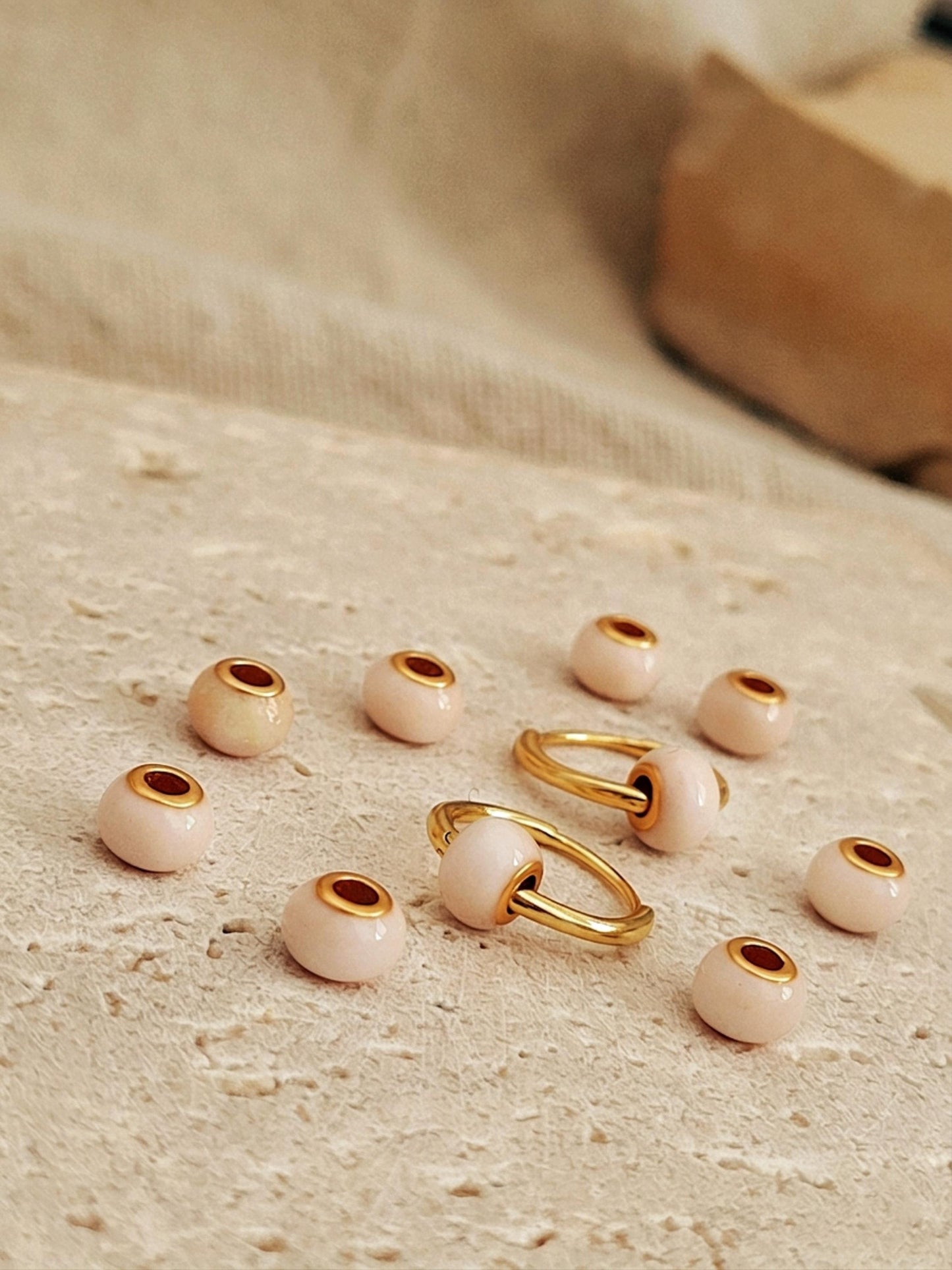 Gold and beige jewelry pieces on a textured surface