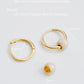 Gold hoop earrings and a gold bead with measurements on a white background