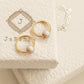 A pair of dainty small gold hoop earrings with white enamel bead displayed on JaBelle Jewellery box.