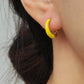 Model wearing small yellow and gold enamel hoop earrings, showcasing their elegant and lightweight design.