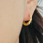 Model wearing small yellow and gold enamel hoop earrings, showcasing their elegant and lightweight design.