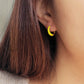 Model wearing small yellow and gold enamel hoop earrings, showcasing their elegant and lightweight design.