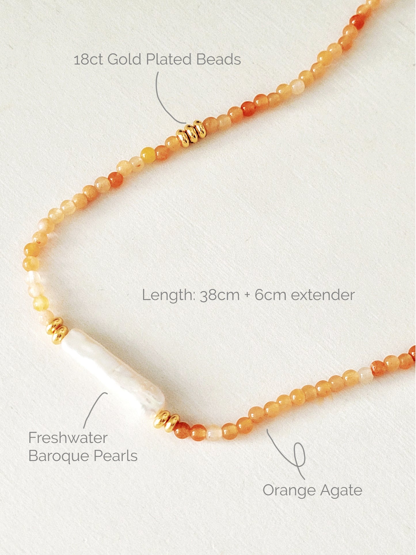 Luxury agate gemstone and freshwater baroque pearl necklace featuring a mix of orange and cream-colored gemstones with gold plated accents.