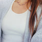 A close-up of a woman wearing a dainty amethyst beaded necklace with faceted purple stones, accented by small gold beads. The necklace with a simple gold chain extending from both sides having purple hues creating a subtle yet stylish look.