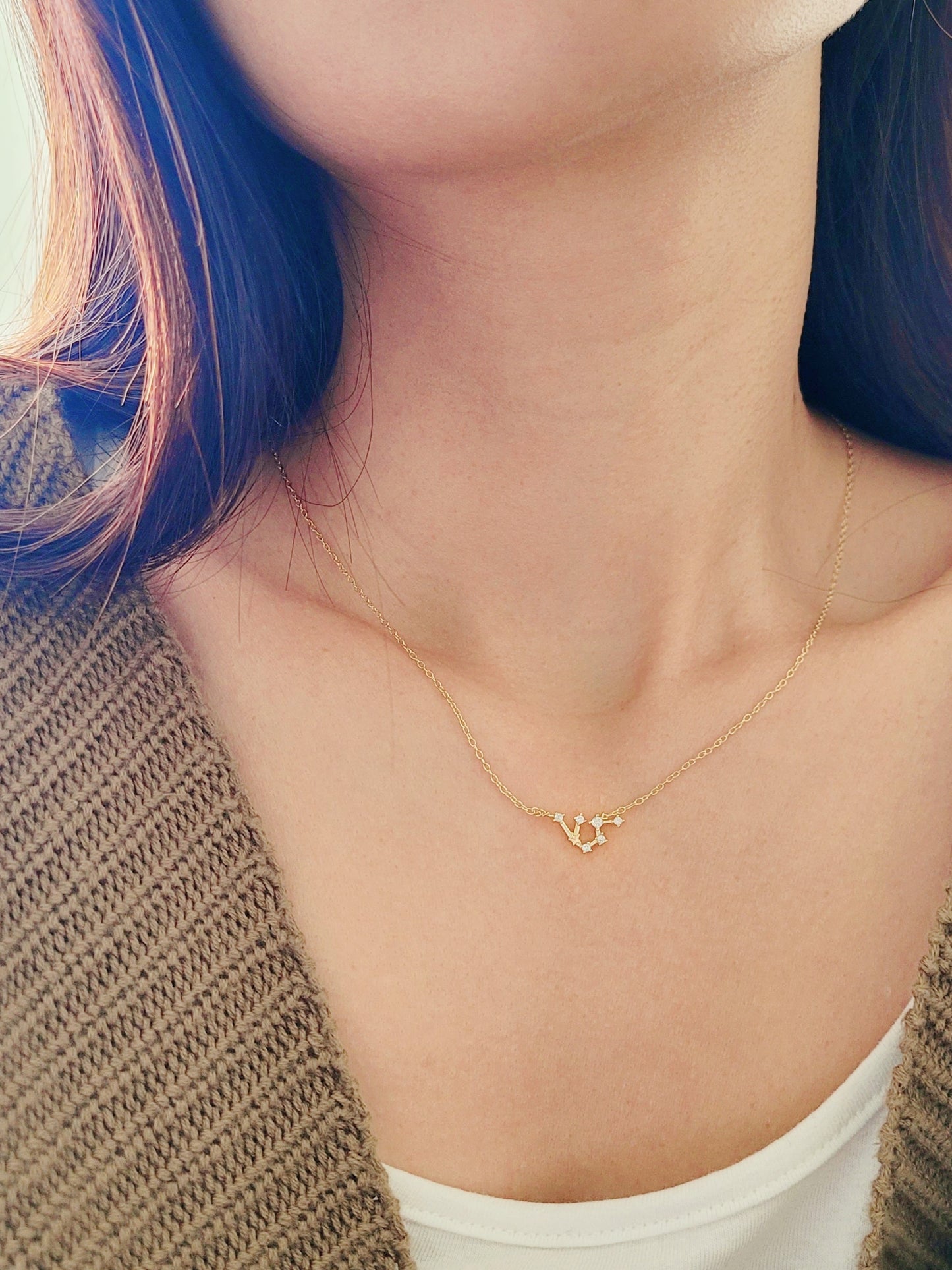 Close-up of a woman wearing a dainty gold Aquarius necklace, showcasing the luxury aesthetic and pendant scale. Crafted in 14k gold vermeil.