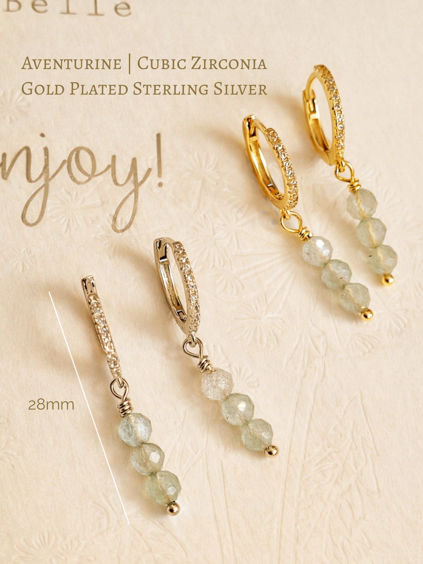 Gold and silver earrings with aventurine beads on a beige background