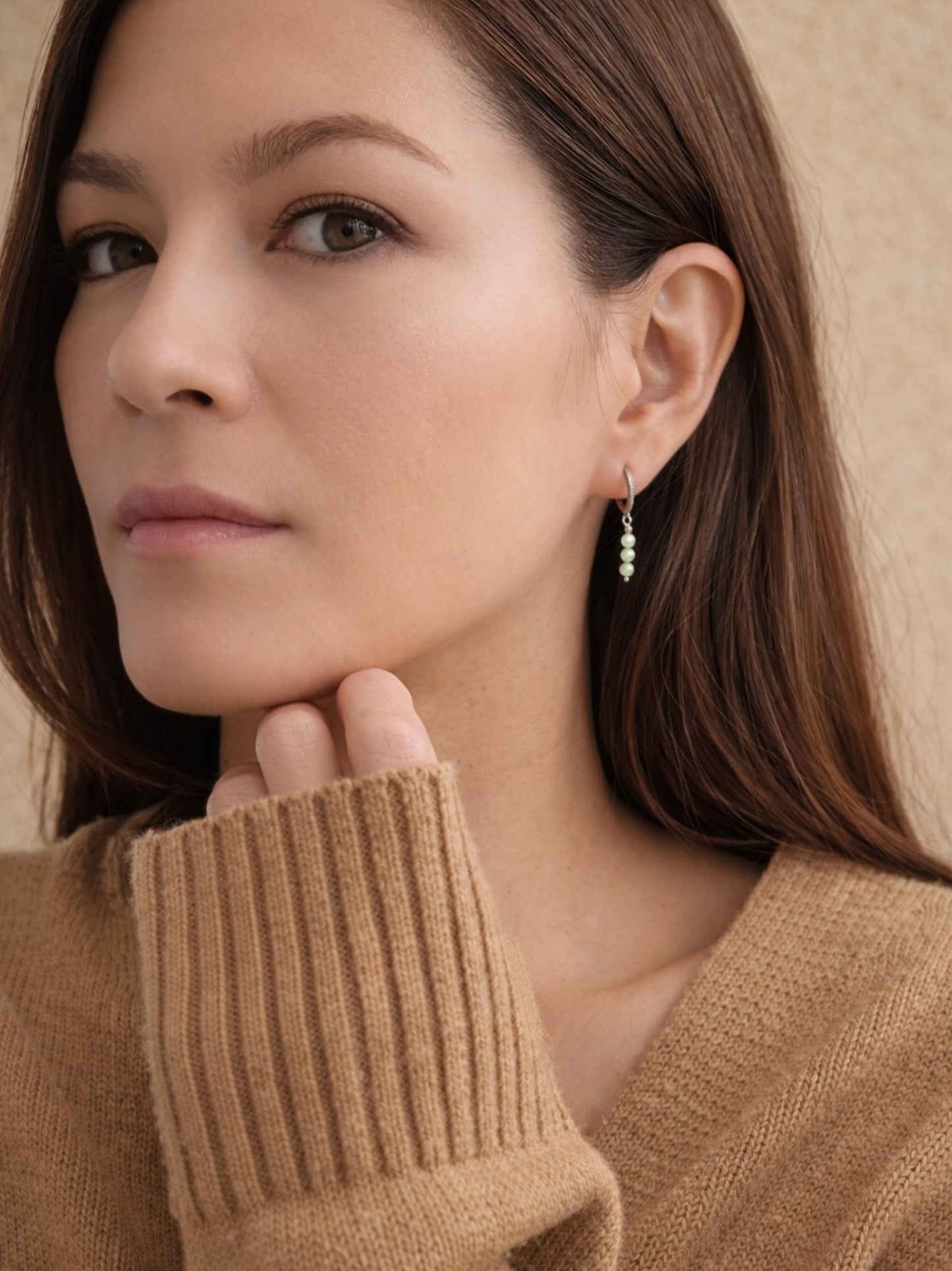 Model wearing dainty green aventurine drop earrings on silver huggie hoops.