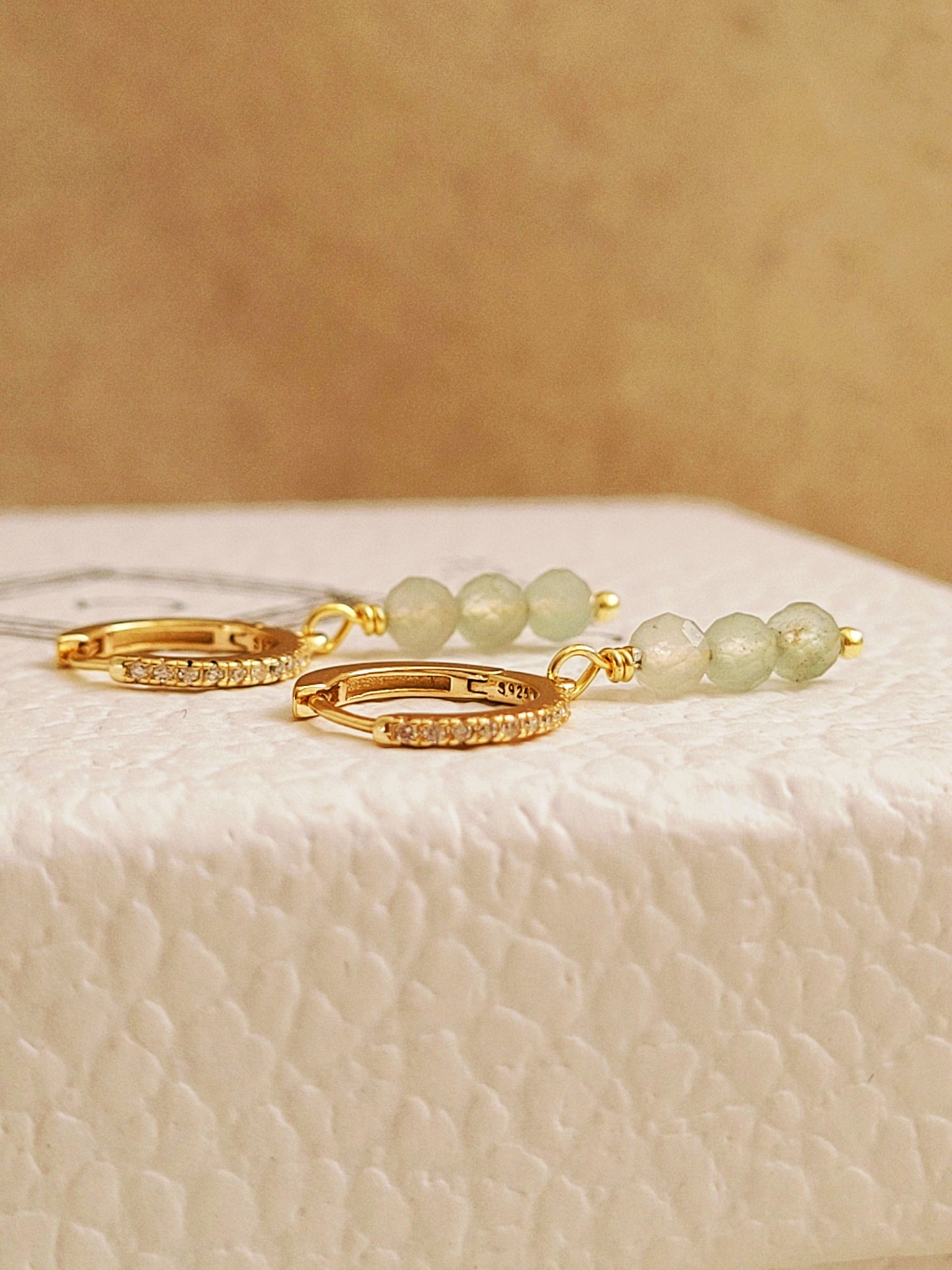 Close up of a pair of green aventurine drop earrings crafted in gold plated sterling silver.
