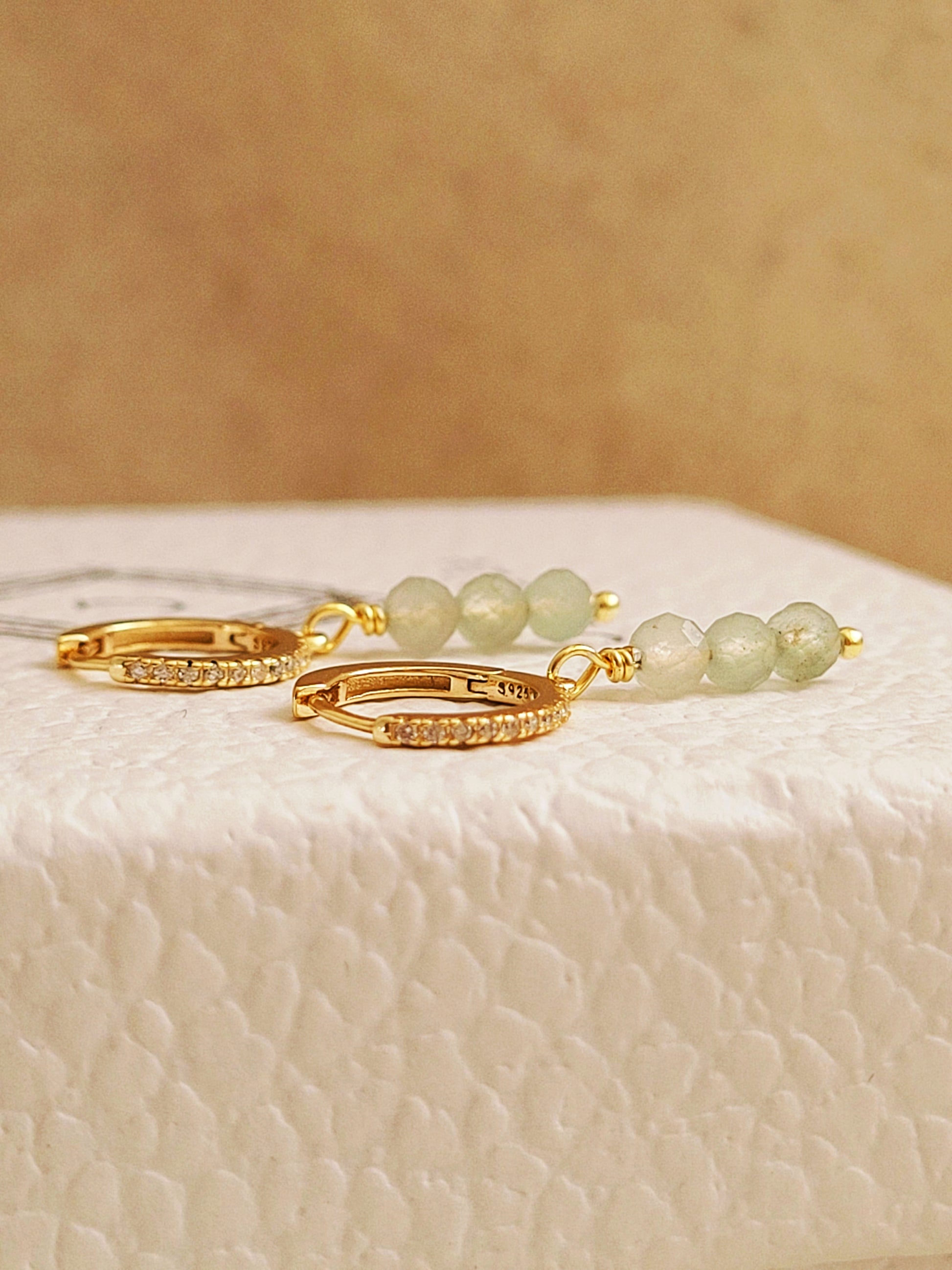 Close up of a pair of green aventurine drop earrings crafted in gold plated sterling silver.