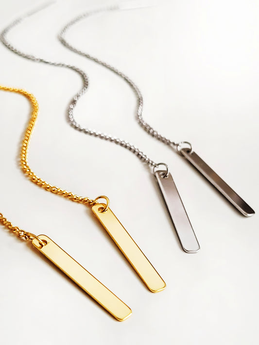 2 pairs of long bar threader earrings in gold and silver displayed on a white surface.