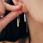 Close-up of a woman wearing gold and silver bar threader earrings.