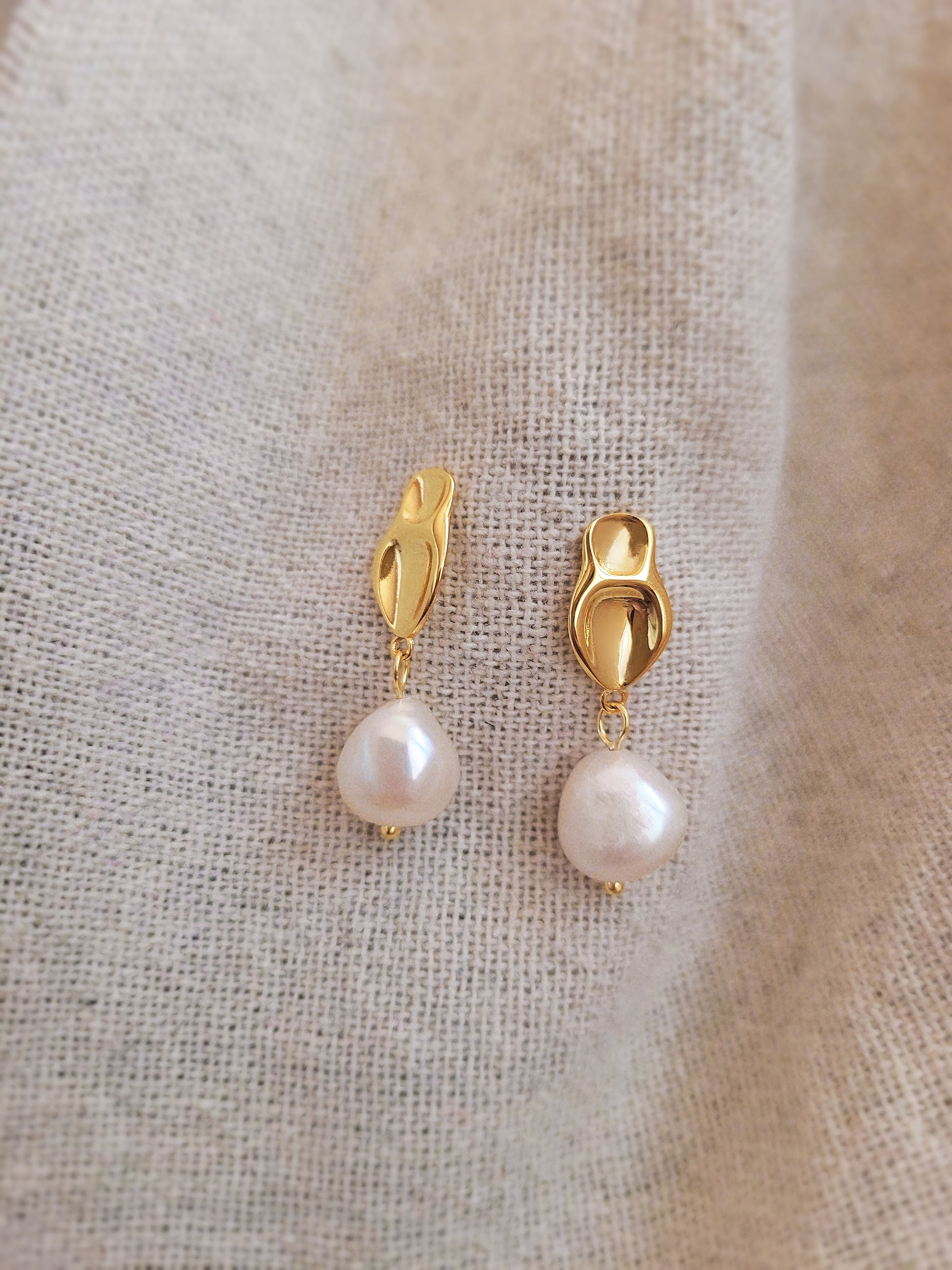 Elegant freshwater pearl dangle earring in gold, highlighting a modern, minimalistic design.