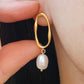 Close-up of baroque pearl drop earrings in gold.