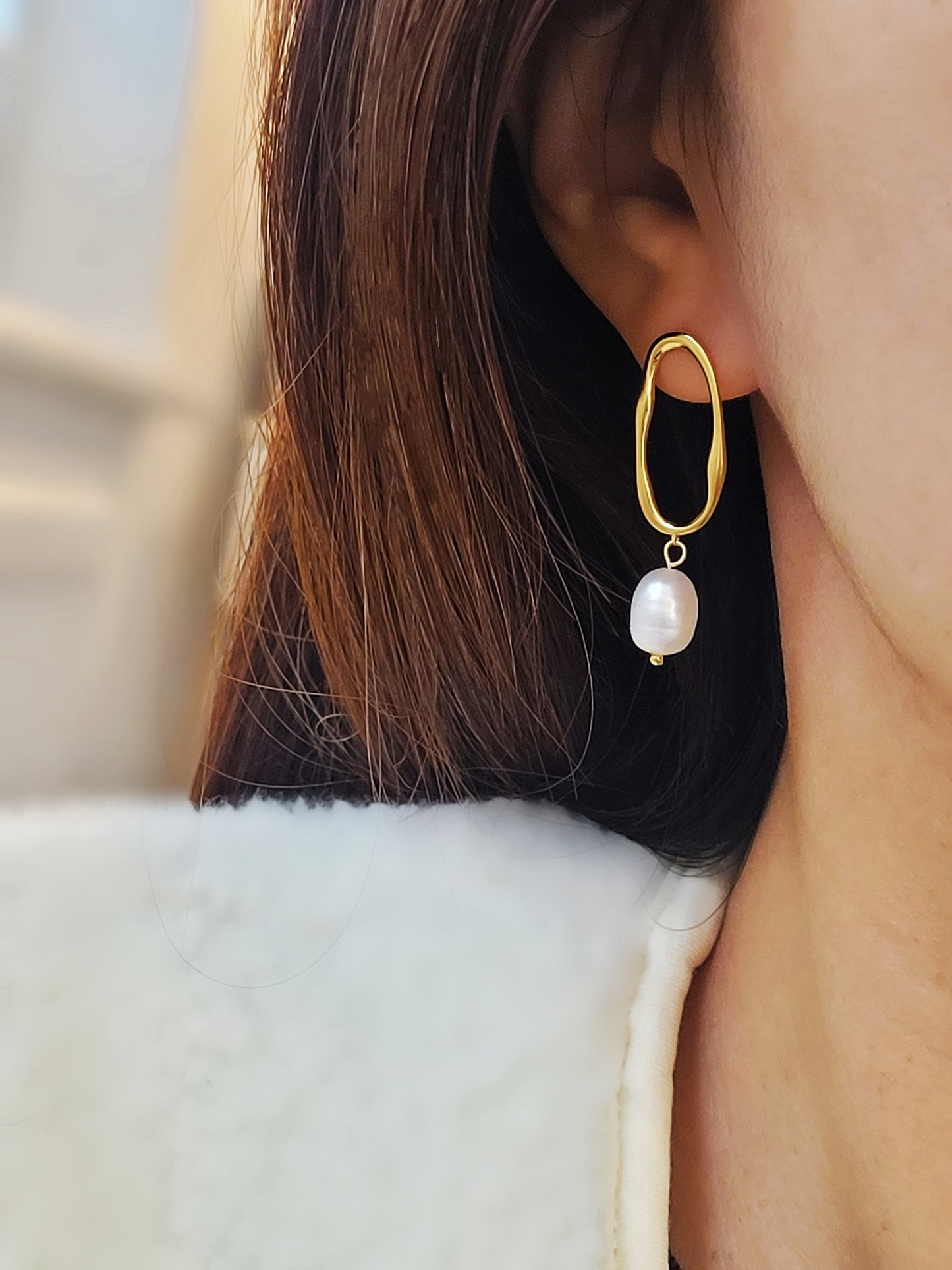 Woman wearing gold hoop earrings with freshwater baroque pearl drop for wedding.