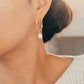 Woman wearing gold hoop earrings with freshwater baroque pearl drop for wedding.