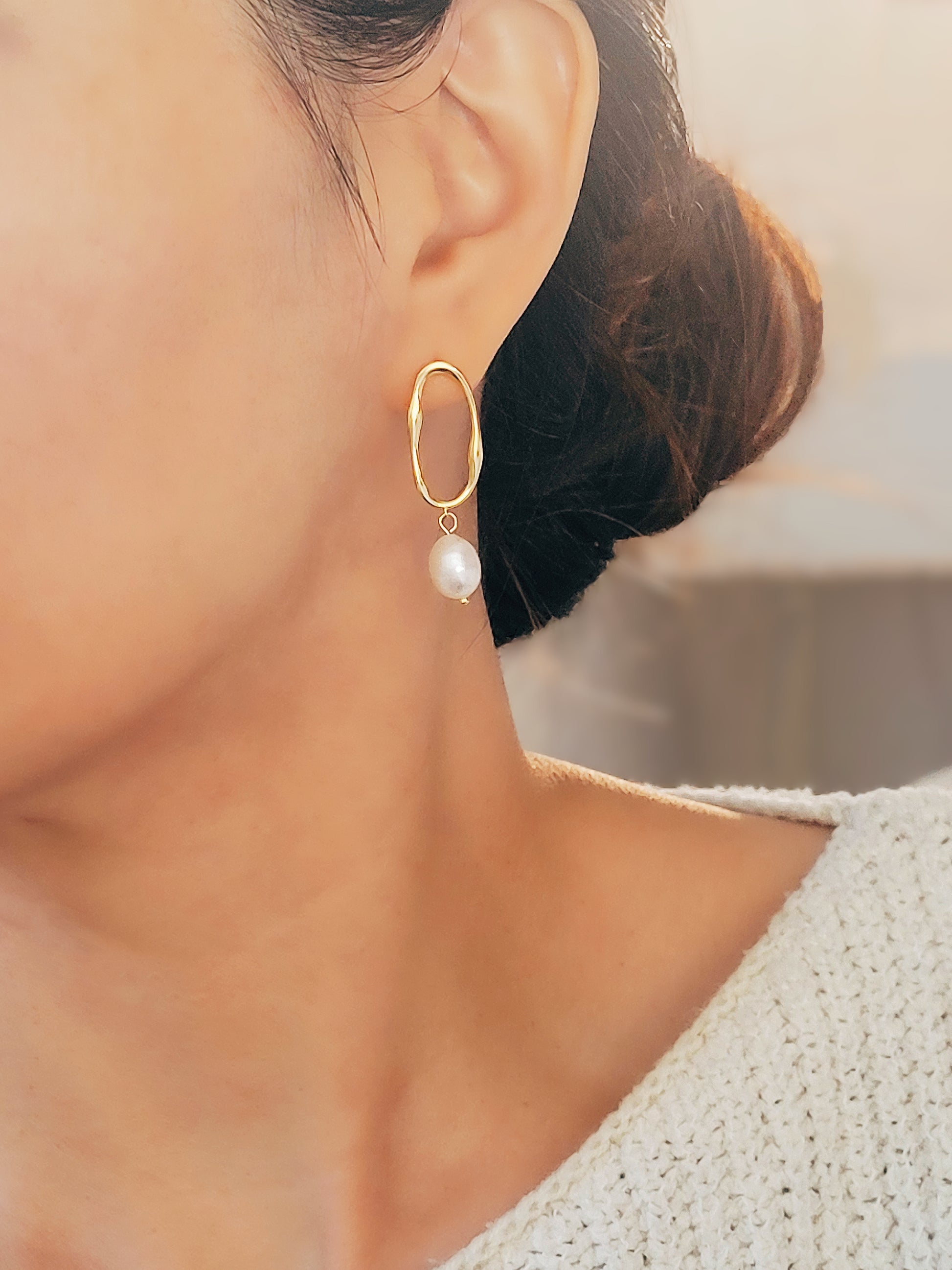 Woman wearing gold hoop earrings with freshwater baroque pearl drop for wedding.