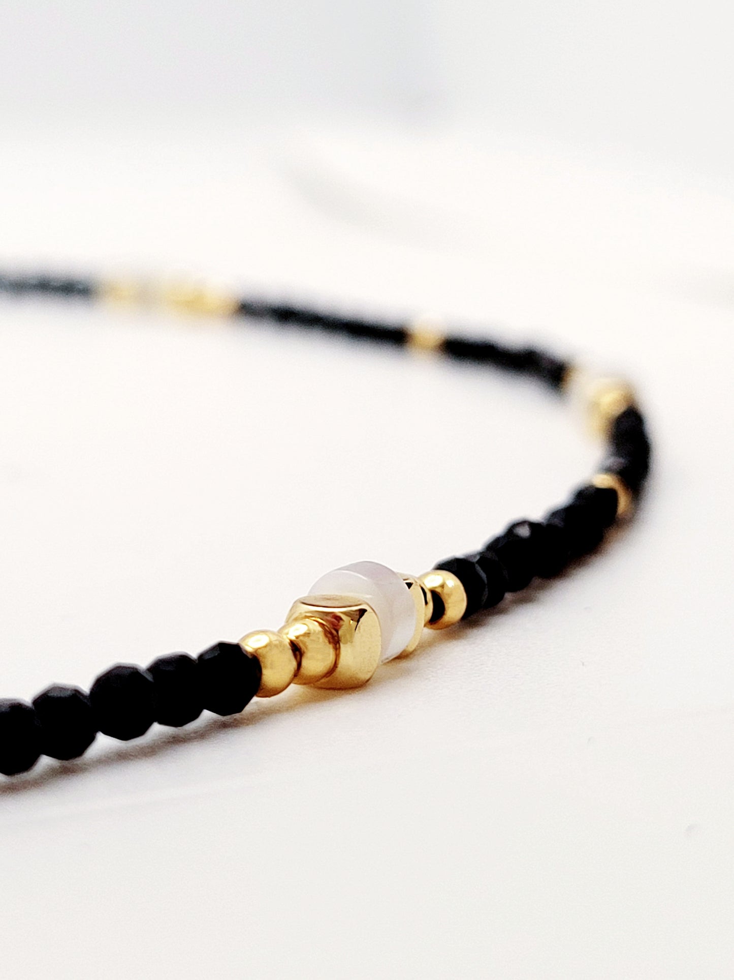 A luxurious black spinel beaded necklace with gold vermeil beads and mother of pearl beads embodying elegance and sophistication for the discerning wearer.