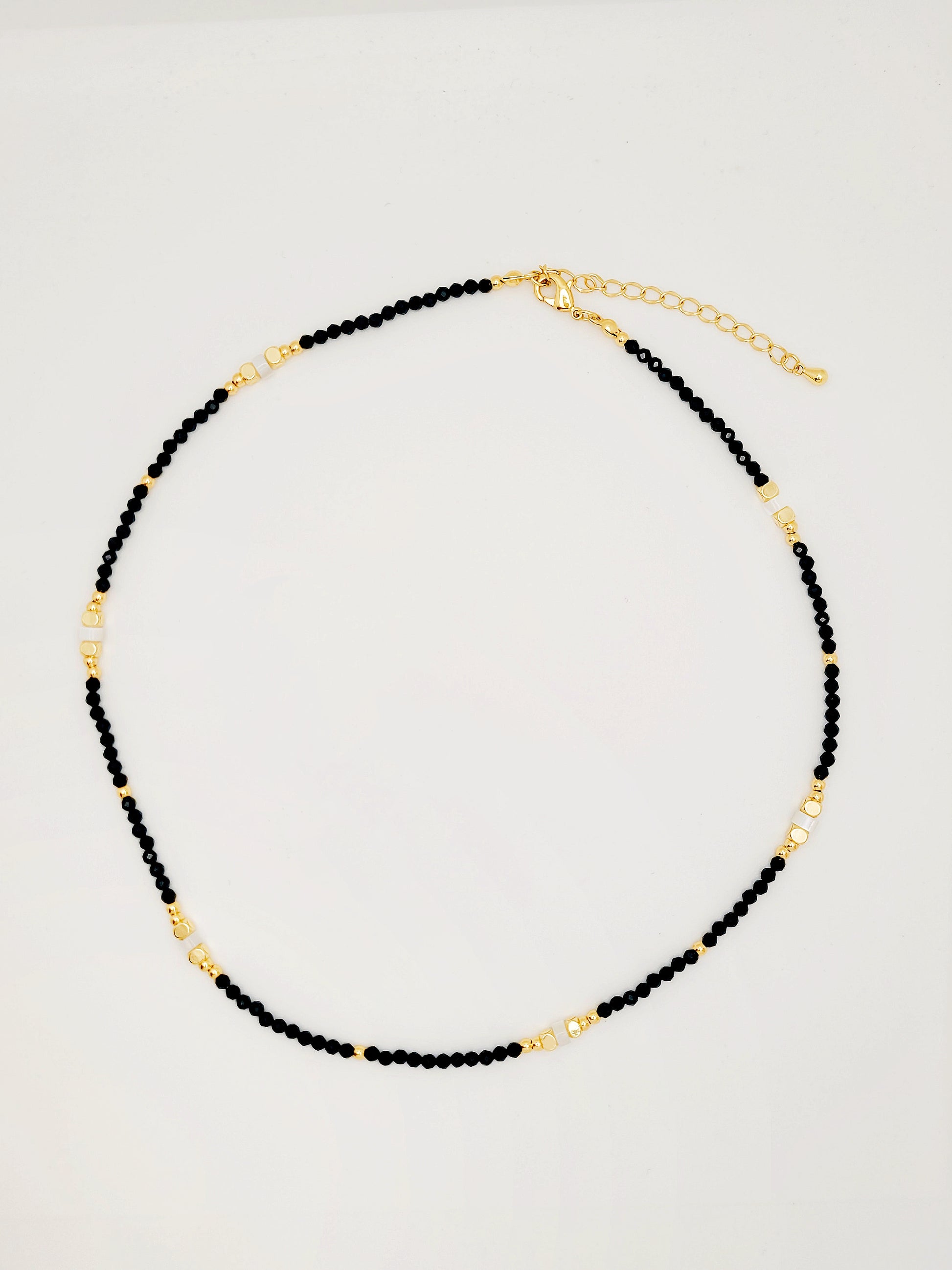 An elegant black spinel beaded necklace adorned with luxurious gold accents and mother of pearl beads exuding sophistication and style.