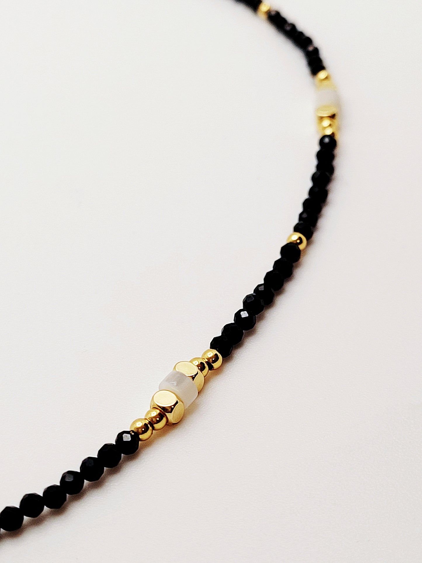 A stylish black and gold beaded necklace featuring exquisite black spinel beads, mother of pearl beads and gold vermeil beads perfect for adding elegance to any outfit.