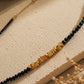 Detailed view of a dainty black spinel gemstone choker necklace with organic 22k gold vermeil nugget displayed on a stone surface.