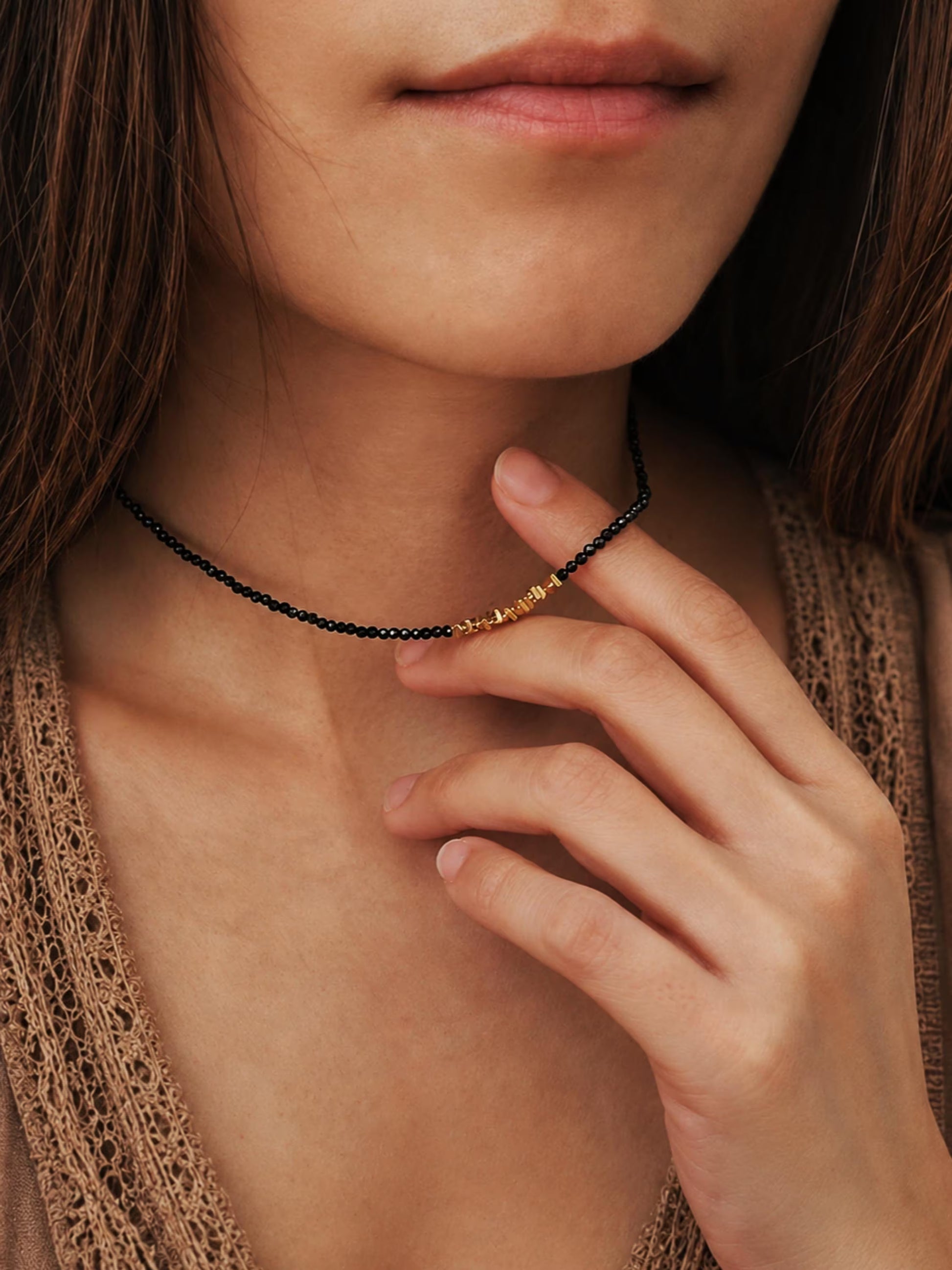 A close-up of a woman wearing a delicate 2mm black spinel beaded choker necklace featuring a center accent cluster of organic, textured 22k gold vermeil nuggets.