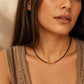 A close-up of a woman in bohemian beige color vest wearing a delicate 2mm black spinel beaded choker necklace featuring a center accent cluster of organic, textured 22k gold vermeil nuggets.