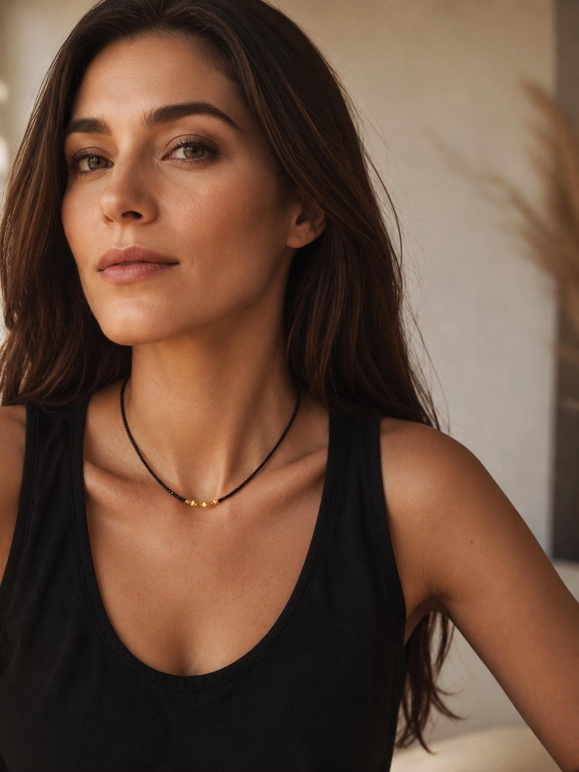 A close-up of a woman wearing a delicate 2mm black spinel beaded choker necklace featuring a center accent cluster of organic, textured 22k gold vermeil nuggets. Timeless elegant style, perfect anniversary gift for her.