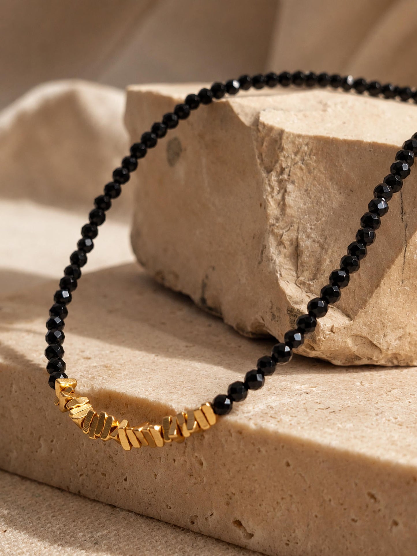 Detailed view of a handmade black spinel gemstone choker necklace with a 23mm section of faceted, organic 22k gold vermeil nugget beads over 925 sterling silver.