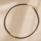 A dainty black spinel gemstone choker necklace with organic 22k gold vermeil nugget displayed on a white surface. 