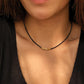 A close-up of a woman wearing a delicate 2mm black spinel beaded choker necklace featuring a center accent cluster of organic, textured 22k gold vermeil nuggets.