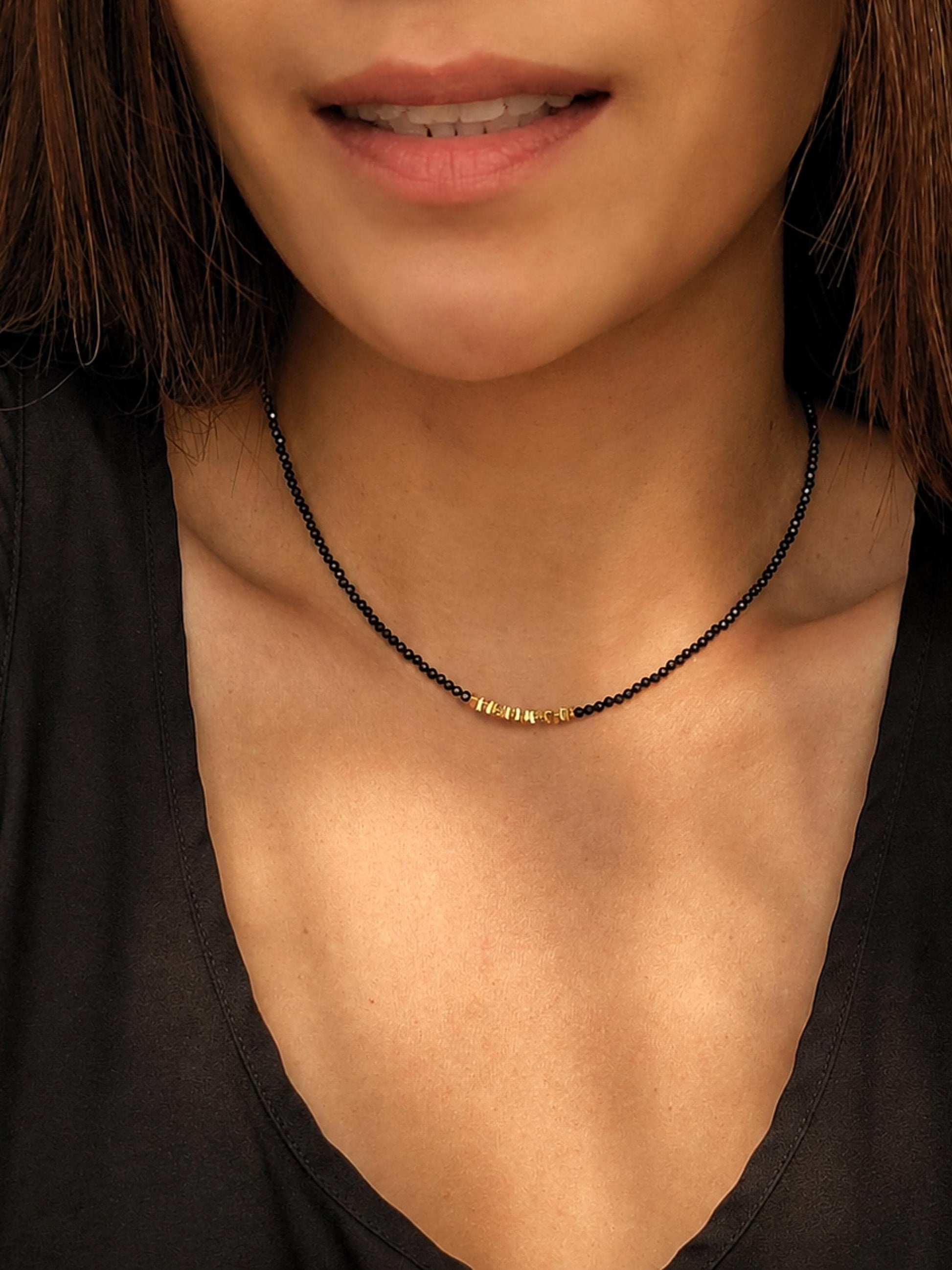 A close-up of a woman wearing a delicate 2mm black spinel beaded choker necklace featuring a center accent cluster of organic, textured 22k gold vermeil nuggets.