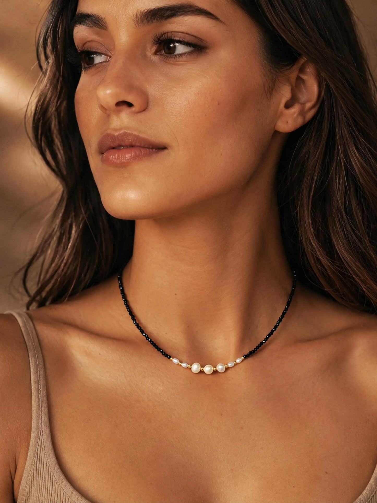 Black spinel and freshwater pearl choker necklace with 18k gold plated sterling silver accents, worn by a woman. Delicate pearl and gemstone necklace for everyday wear, layering and elegant bridal jewellery.