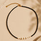 Black spinel gemstone choker necklace featuring freshwater pearls and 18k gold plated sterling silver beads, displayed on a neutral beige background. Minimalist pearl necklace for weddings, bridesmaids and everyday styling.