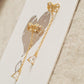 A pair of dainty gold butterfly earrings with long chain details on a white surface
