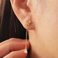 Dainty 18k gold vermeil butterfly stud earring with a delicate chain drop and sparkling pear-cut cubic zirconia stone worn on a model.
