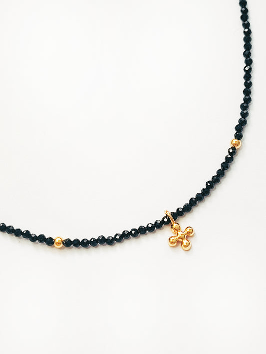 Faceted black spinel bead choker with a gold clover pendant that’s two sided, showing gold finishing on one side and zircon embellishments on the other.