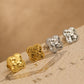 Close up of a set of dainty clover stud earrings in 18k gold vermeil and 925 sterling silver showing the intricate textured detail on an aesthetic beige stone surface, perfect gift for her