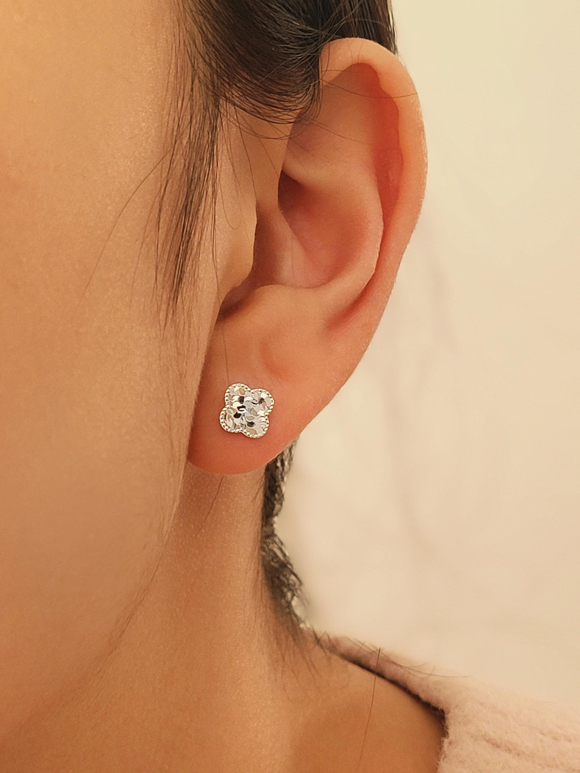Dainty 925 sterling silver four-leaf clover stud earring worn on a model, featuring a textured finish for a minimalist everyday look.