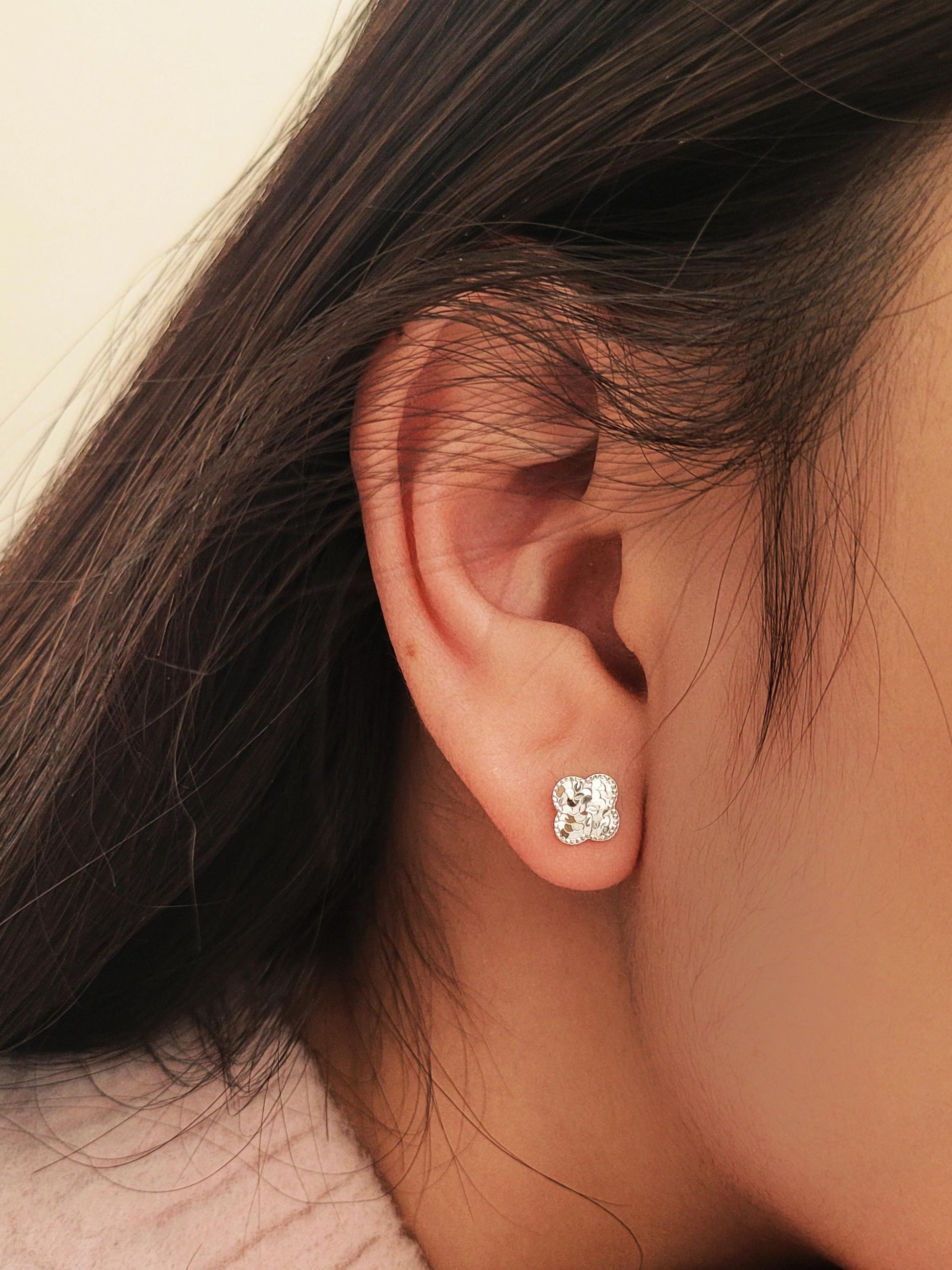 Dainty 925 sterling silver four-leaf clover stud earring worn on a model, featuring a textured finish for a minimalist everyday look.